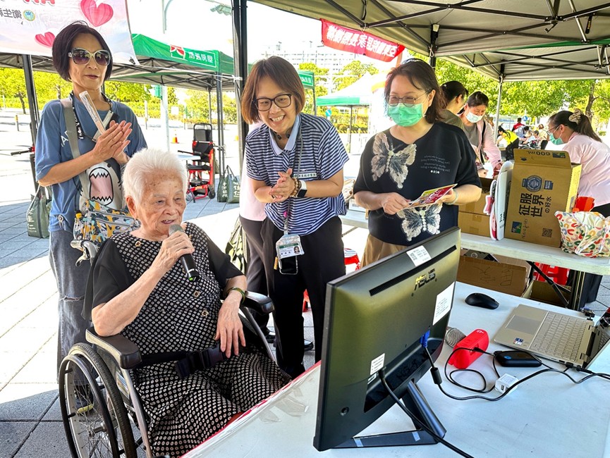 無障礙運輸公益接送 伴長照家庭野餐趣 95歲的翁奶奶(左前)在卡拉OK攤位開心高歌,氣氛溫馨歡樂。(圖/北台灣無障礙運輸產業工會 提供)