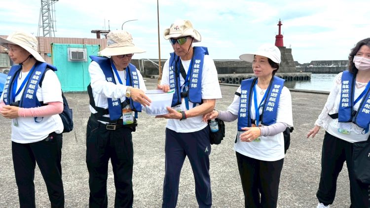 《圖說》大家將魚苗置於水桶中,精準掌握時間、角度與力道接力傳遞,讓魚苗平安回歸大海。(靈鷲山佛教教團提供)
